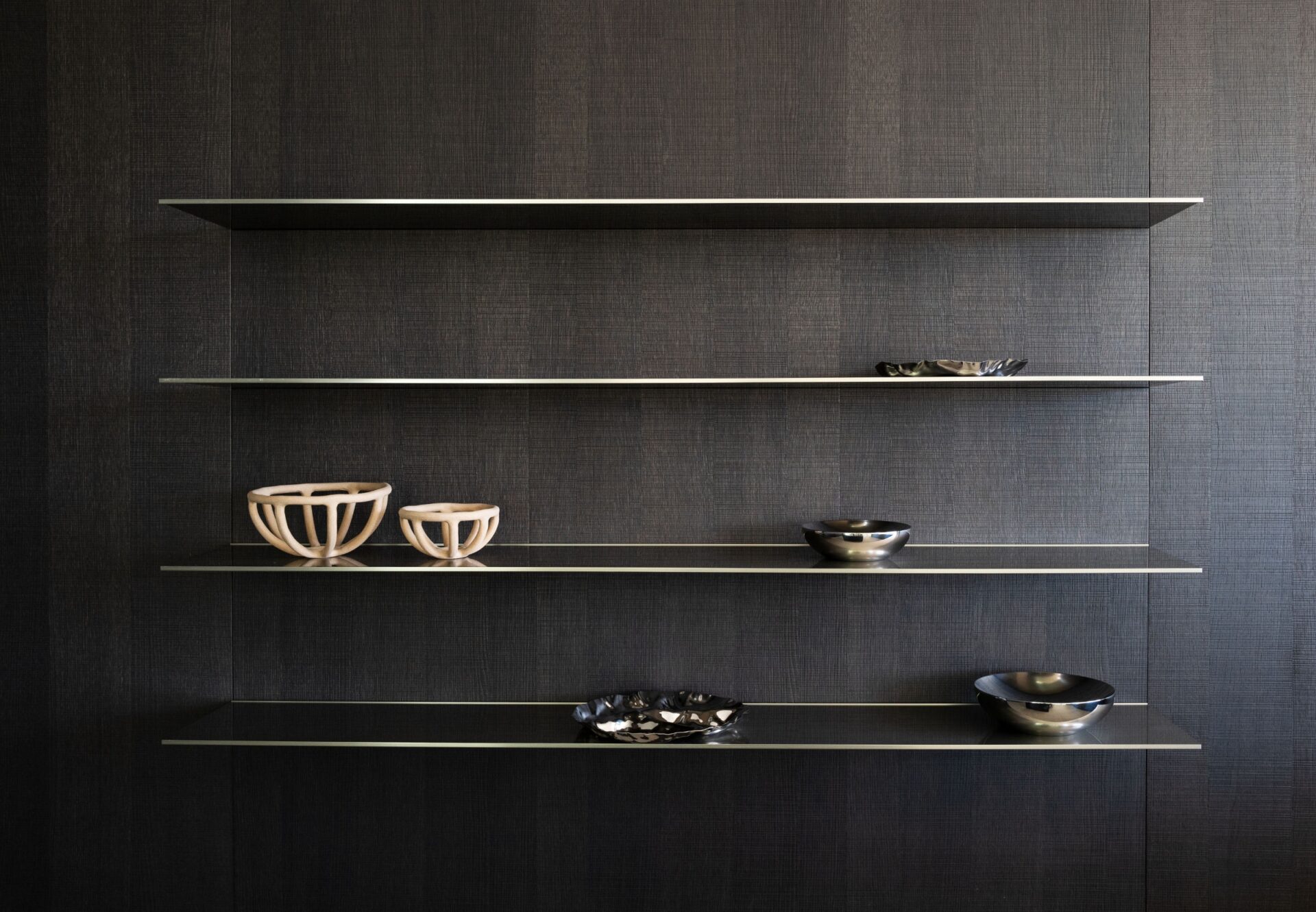 Floating shelves on dark oak wall displaying ceramic bowls and decorative objects in minimalist style.