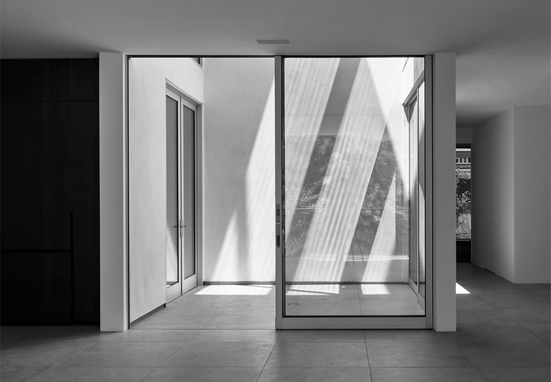 View from living room looking into central open-air courtyard of two-bedroom residence with geometric light patterns.