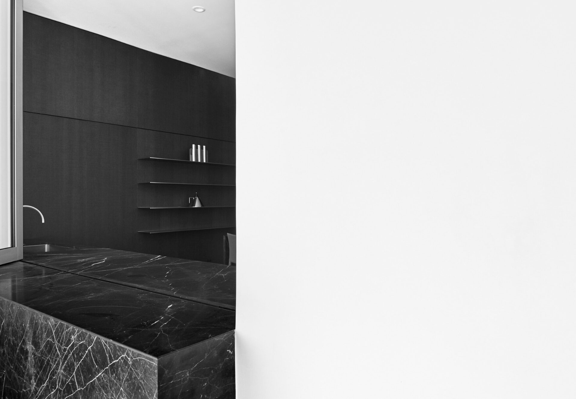 View from terrace through open accordion-style windows into spacious two-bedroom kitchen with dark cabinetry.
