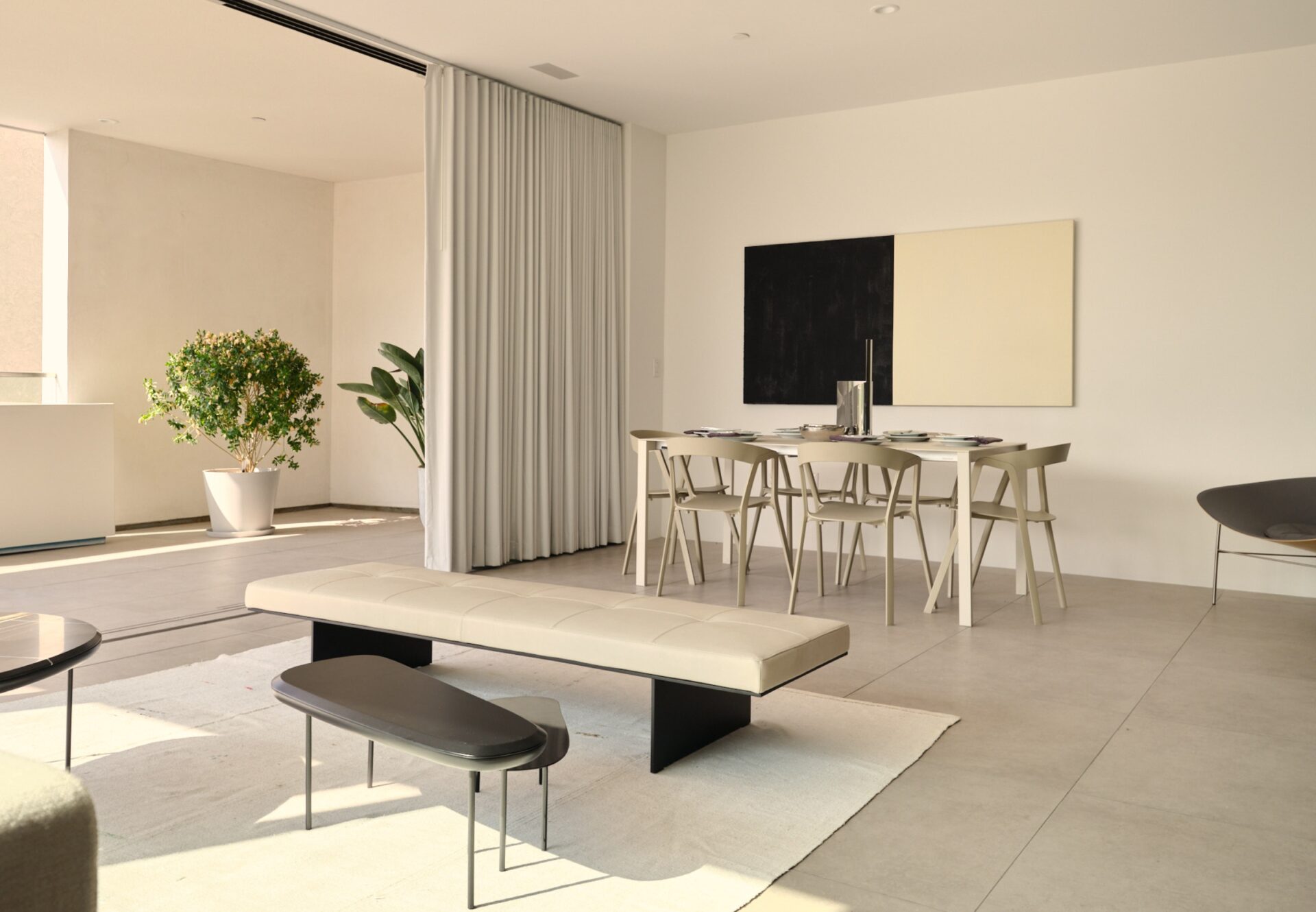 Open-concept dining and lounge area with minimalist decor, natural light, and neutral tones.