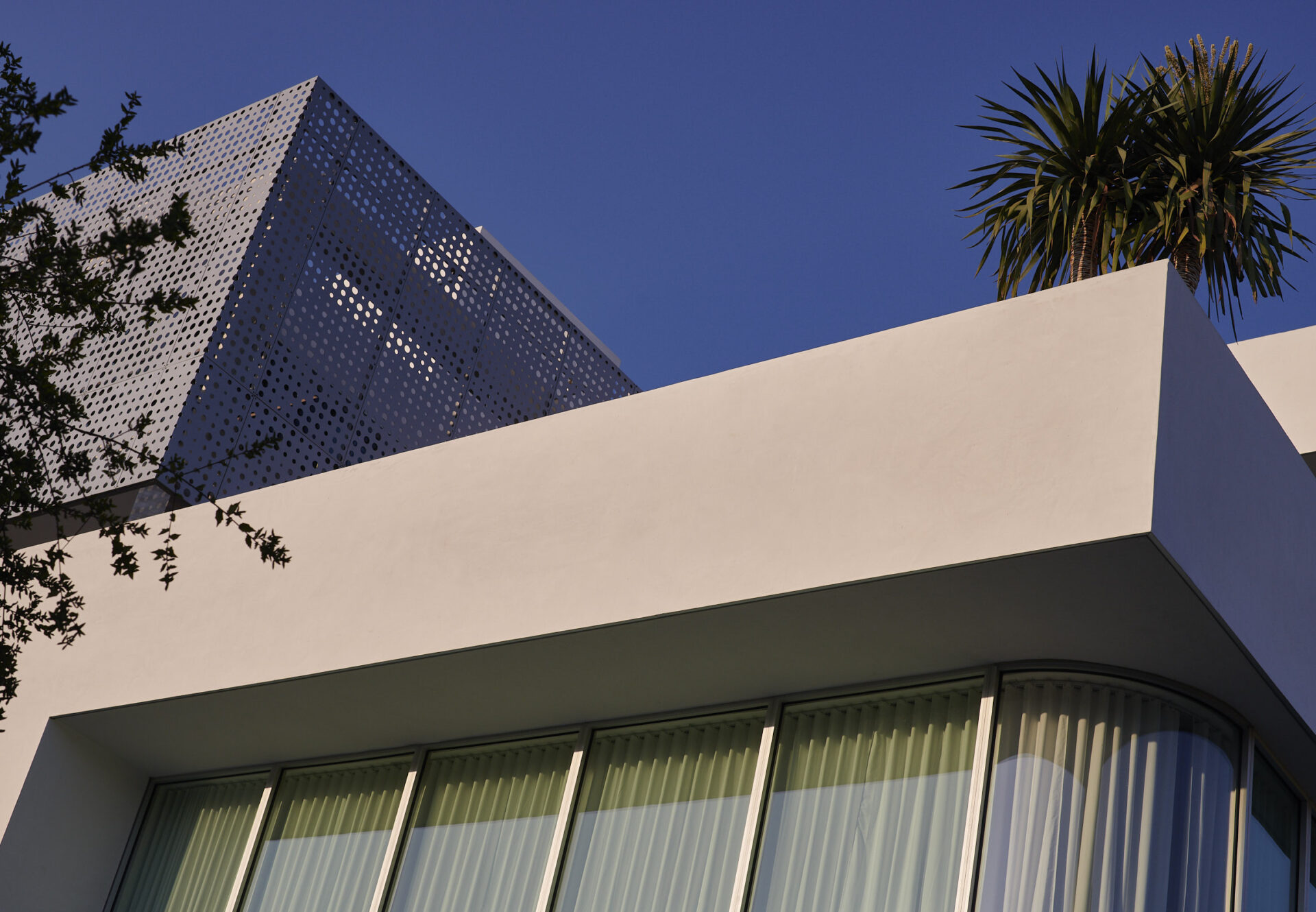 Front facade of Asteras Kings showing corner residence with curved glass windows and perforated metal screen above.