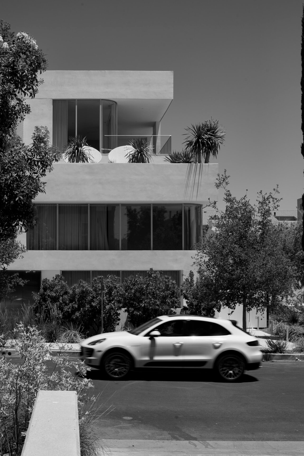 Black-and-white view of Asteras Kings from Kings Road, with a white car passing in front of the modern luxury apartment building.