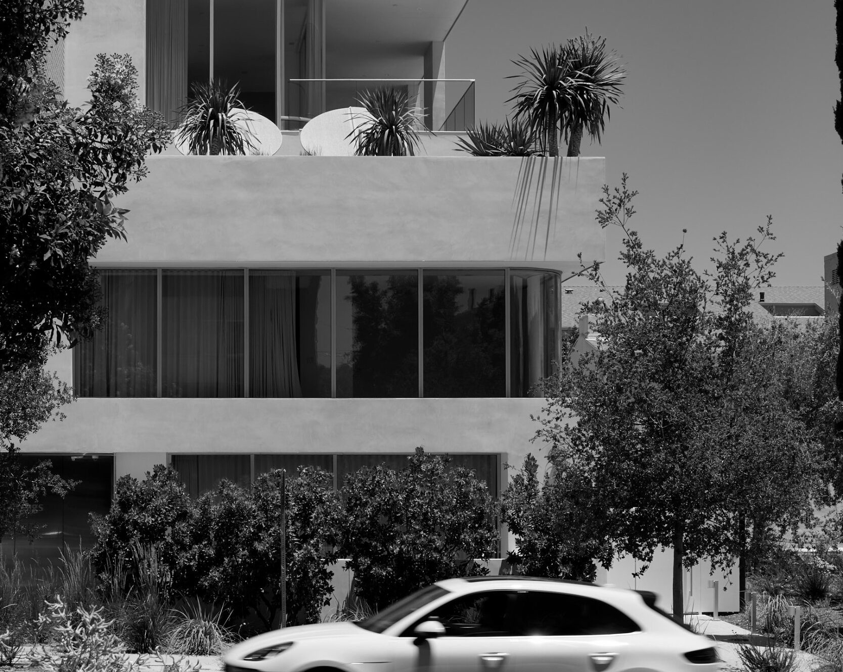 Black-and-white view of Asteras Kings from Kings Road, with a white car passing in front of the modern luxury apartment building.