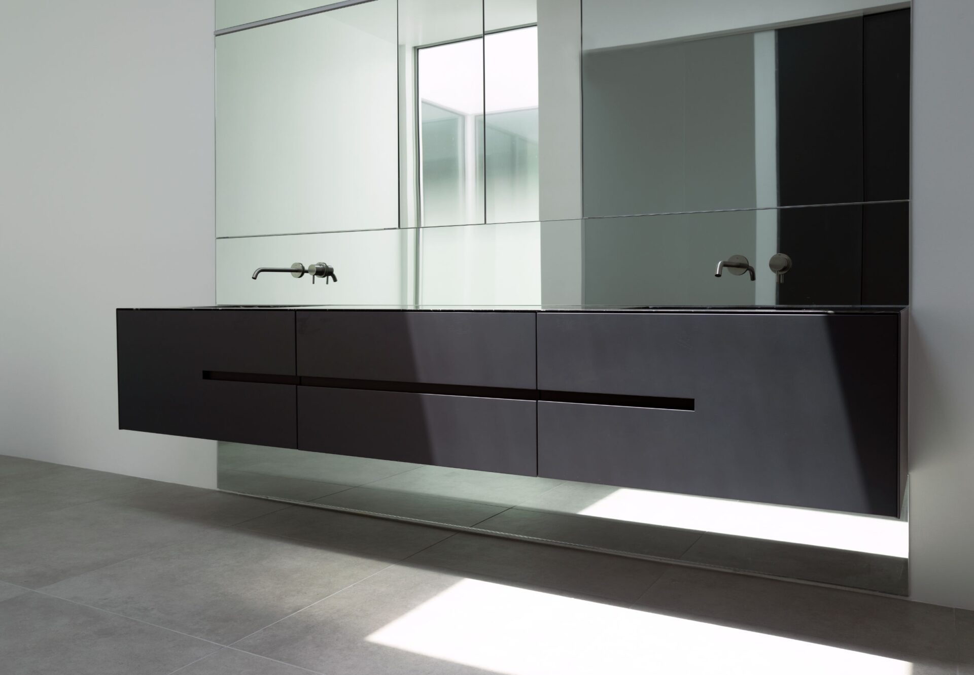 Bright bathroom with floating black dual-sink vanity, mirrored cabinet, and wall-mounted faucets.