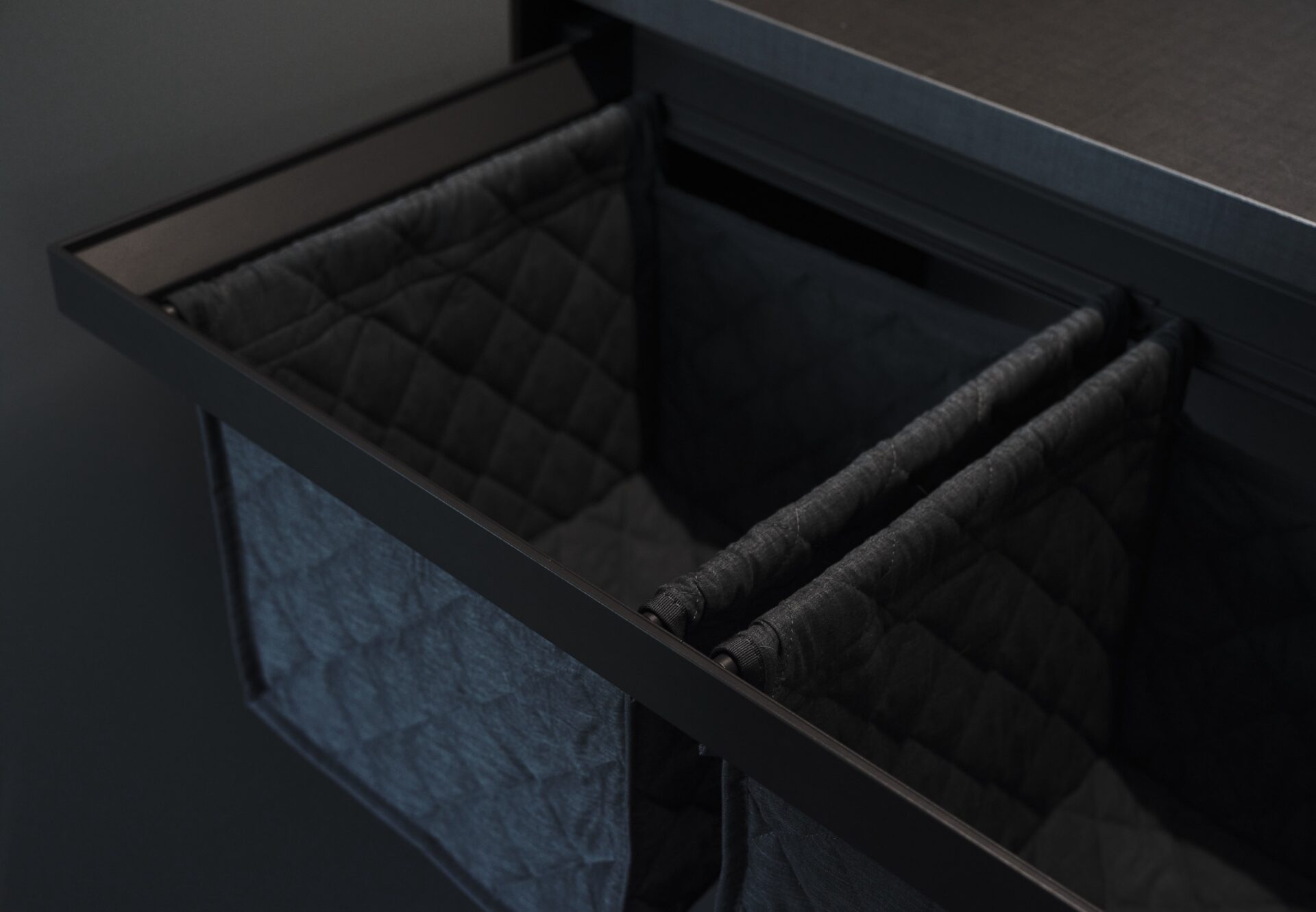 Built-in drawer with quilted dual laundry hamper inserts.