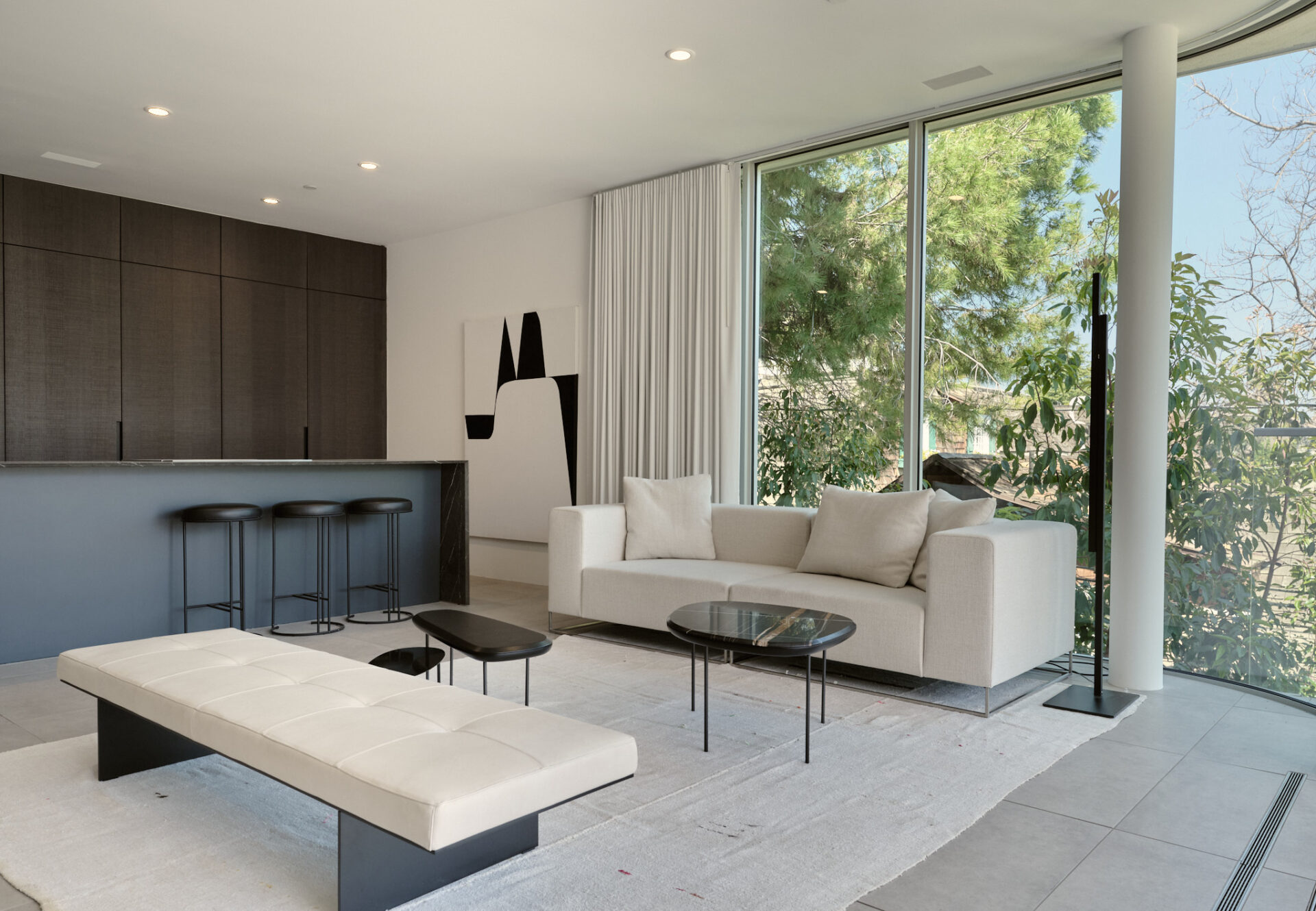 Corner one-bedroom living room with dark oak cabinetry, modern decor, and floor-to-ceiling windows overlooking greenery.
