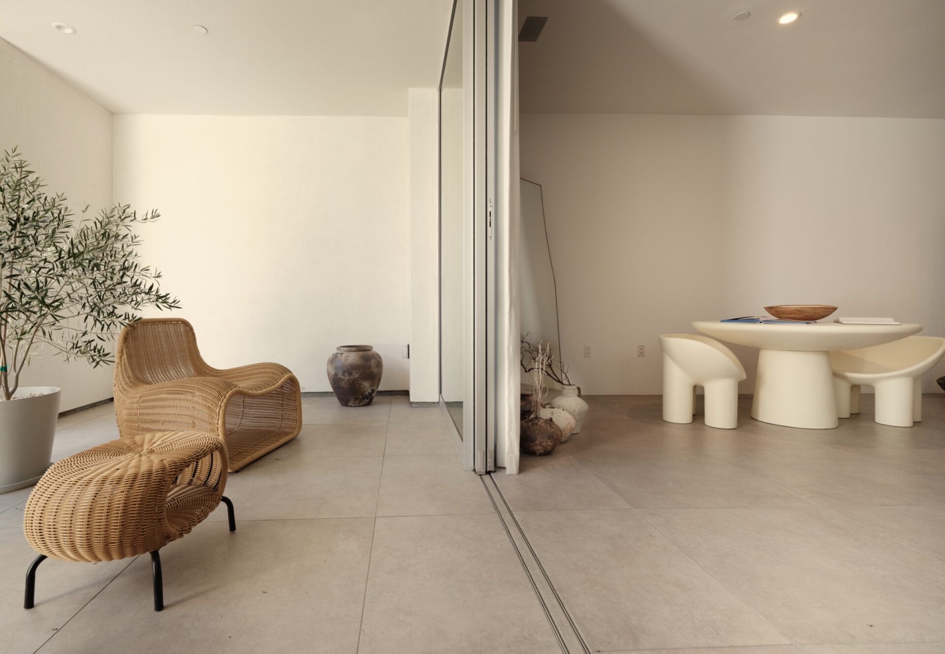 Corner one-bedroom with indoor dining area opening to a private terrace with lounge seating and potted greenery.