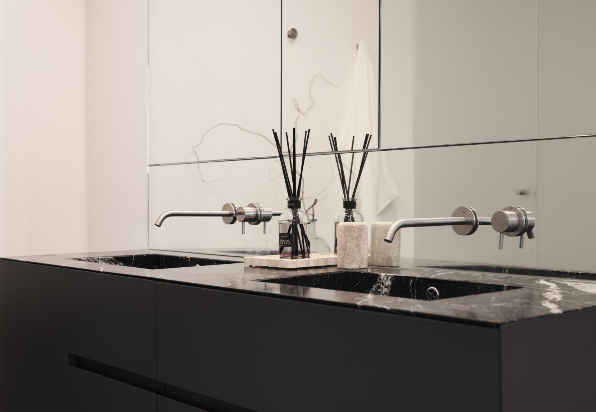Double-sink vanity with marble countertop, wall-mounted faucets, and mirrored cabinetry in a luxury en suite bathroom.