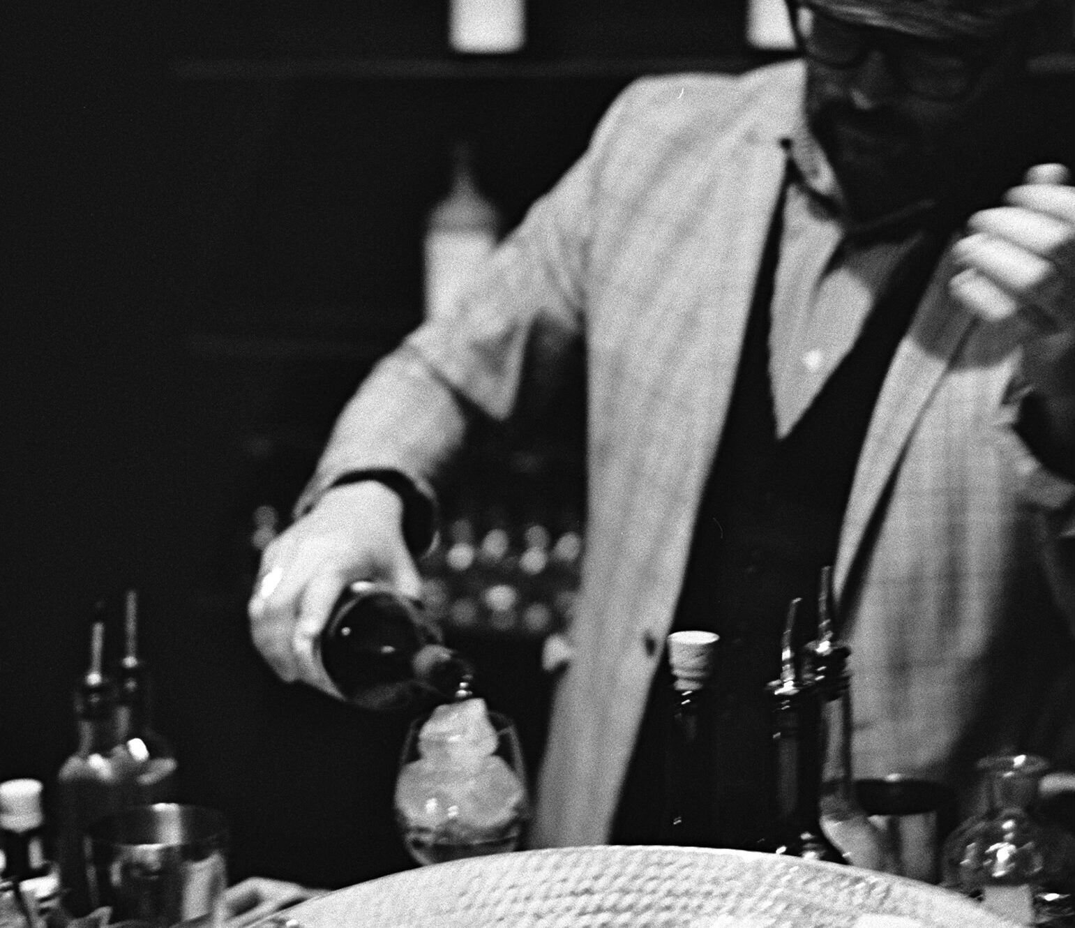 Bartender preparing a cocktail at an evening event on the rooftop terrace, hosted exclusively for residents in a cozy and lively lounge setting.