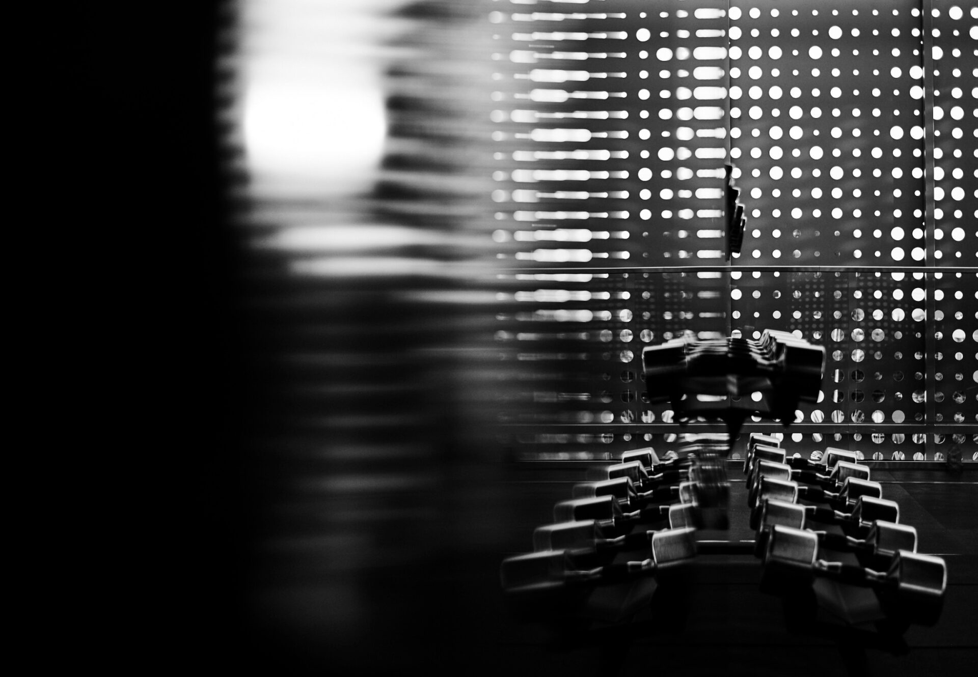 Black-and-white photo of fitness equipment in the penthouse-level studio, framed by perforated metal panels.