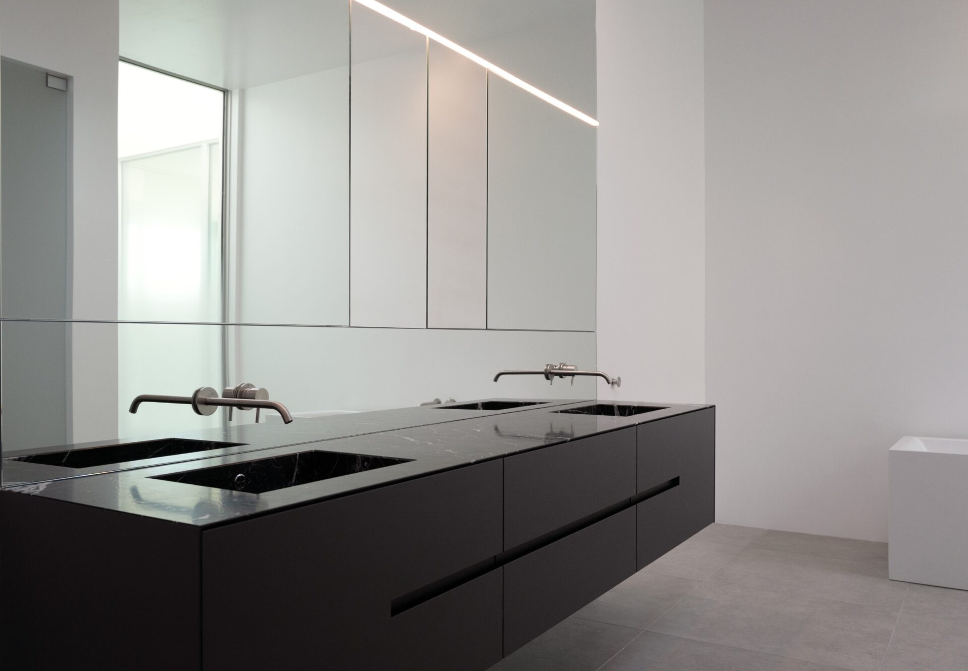Floating double vanity with wall-mounted faucets set in mirror, flanked by mirrored cabinetry.