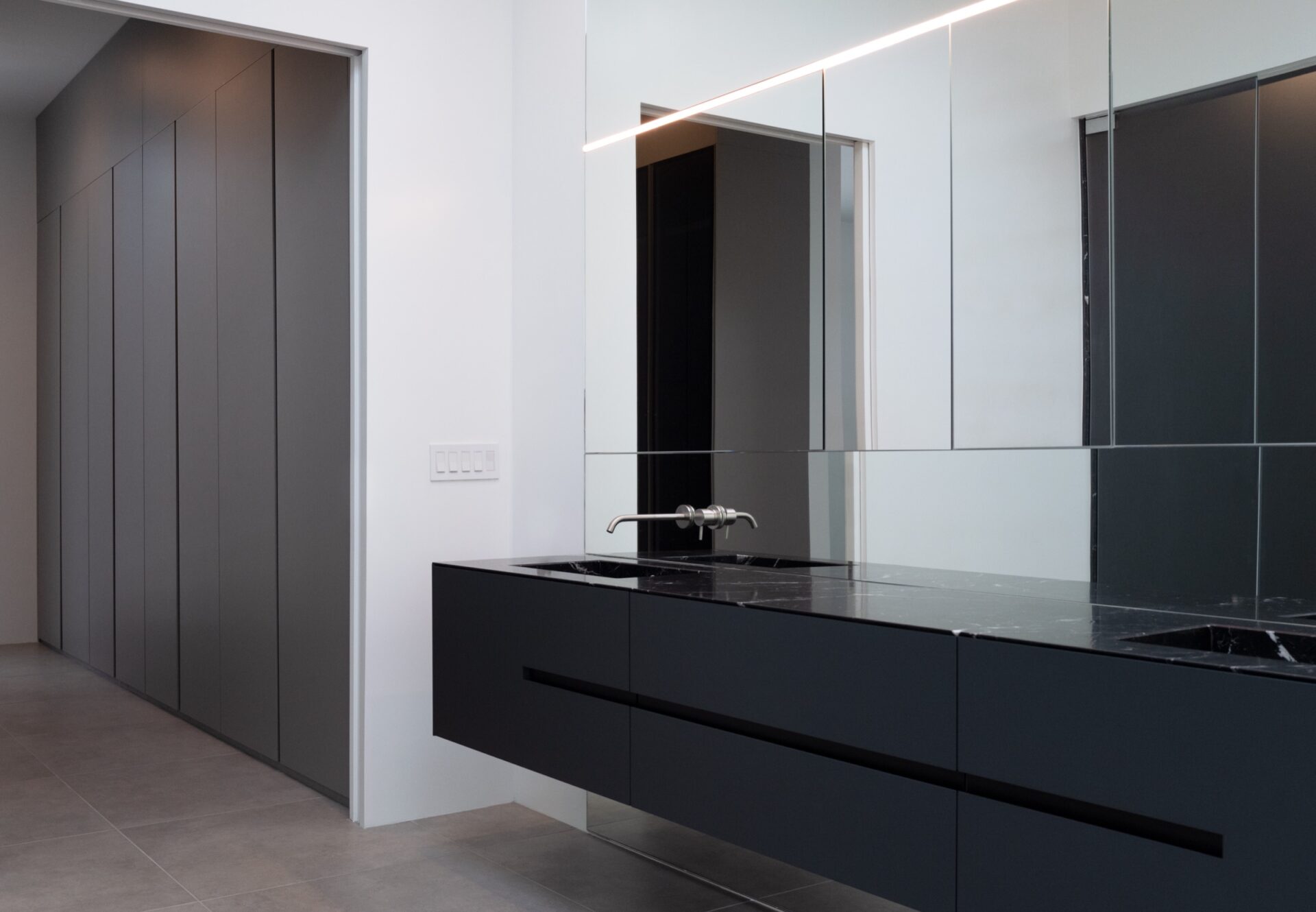 Floating black vanity with integrated sink and mirrored cabinet in a bright en suite bath with built-in hallway closet.