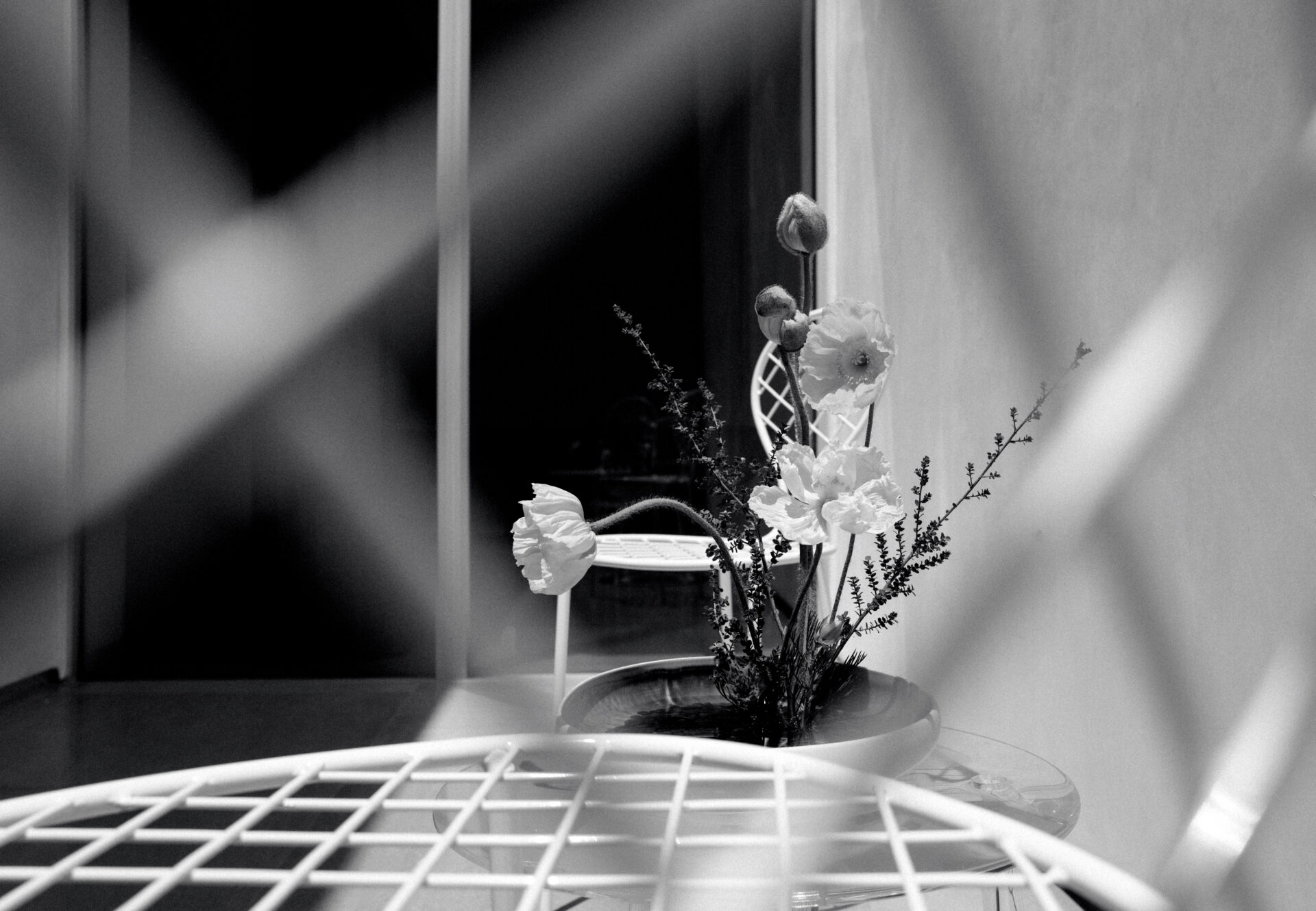 Close-up of a floral arrangement on a patio table, partially framed by a geometric lattice in the foreground.
