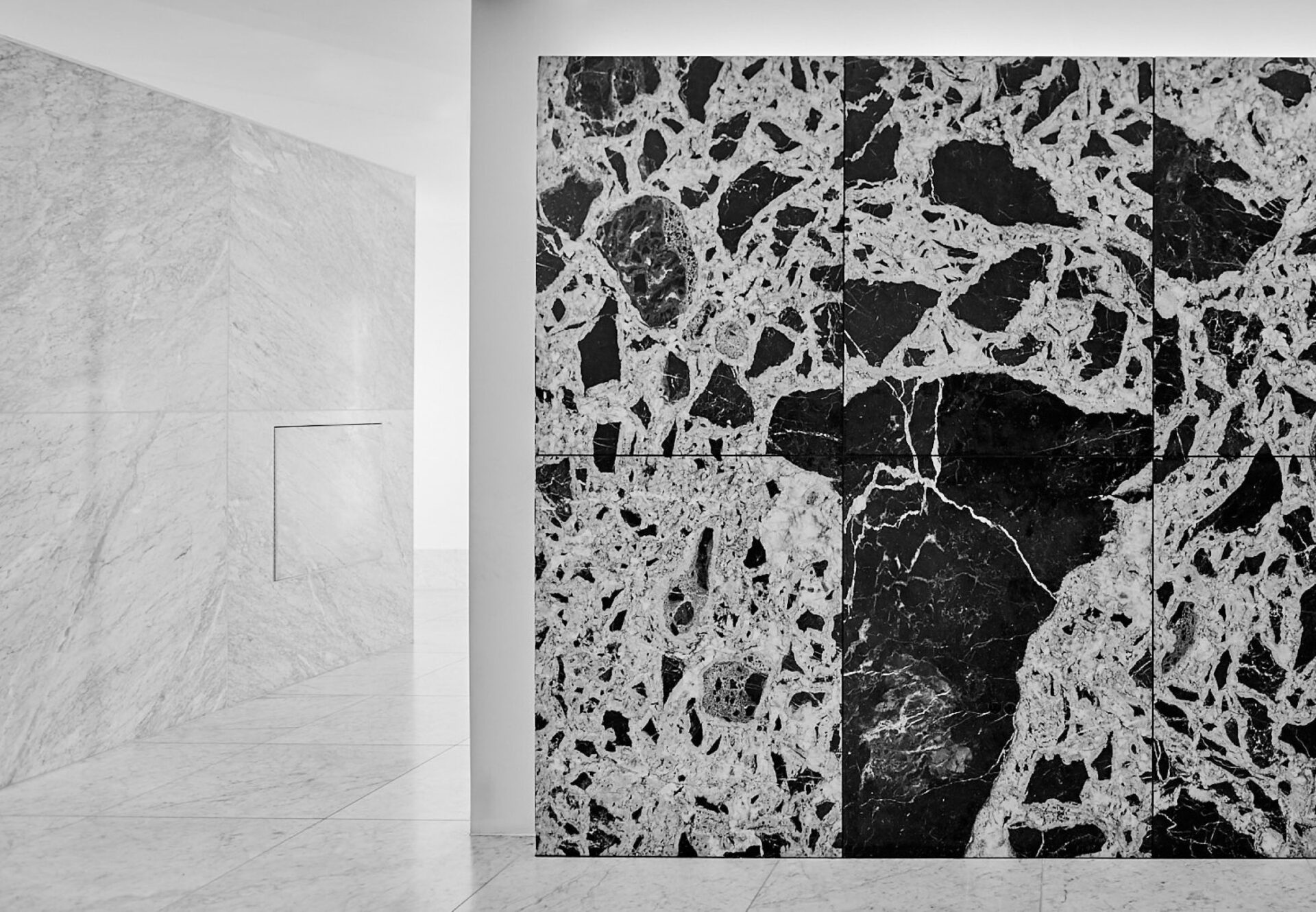 Architectural detail of white and black marble lobby walls, softly illuminated by recessed ambient lighting.