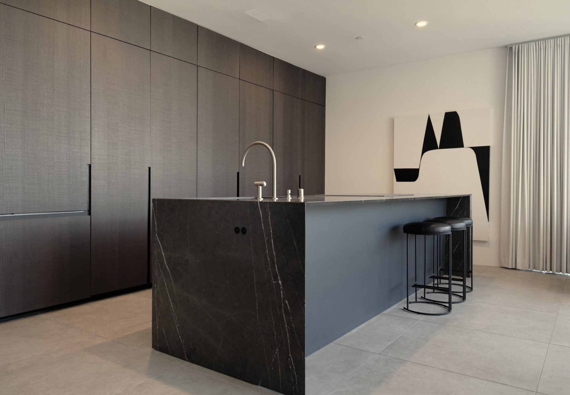 Modern kitchen featuring a waterfall marble kitchen island, integrated dark oak wood cabinetry, and abstract wall art.