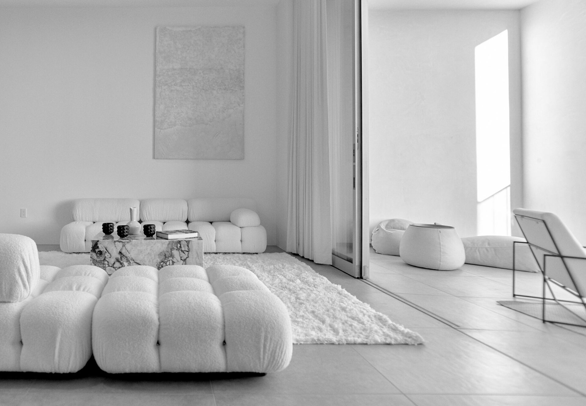 Penthouse living room with modular tufted seating, plush rug, and sliding glass doors leading to a private terrace.