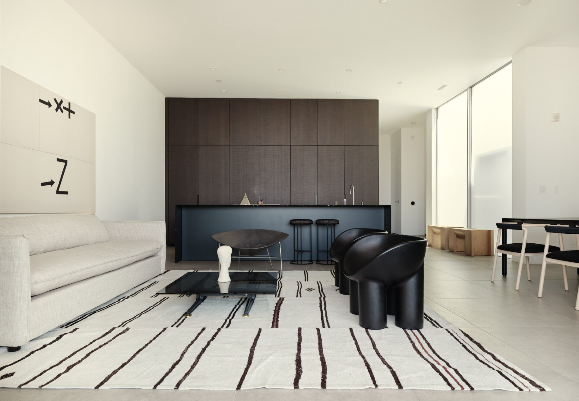 Interior view of penthouse one-bedroom with dark oak kitchen, minimalist decor, and sunlit atrium near the entrance.