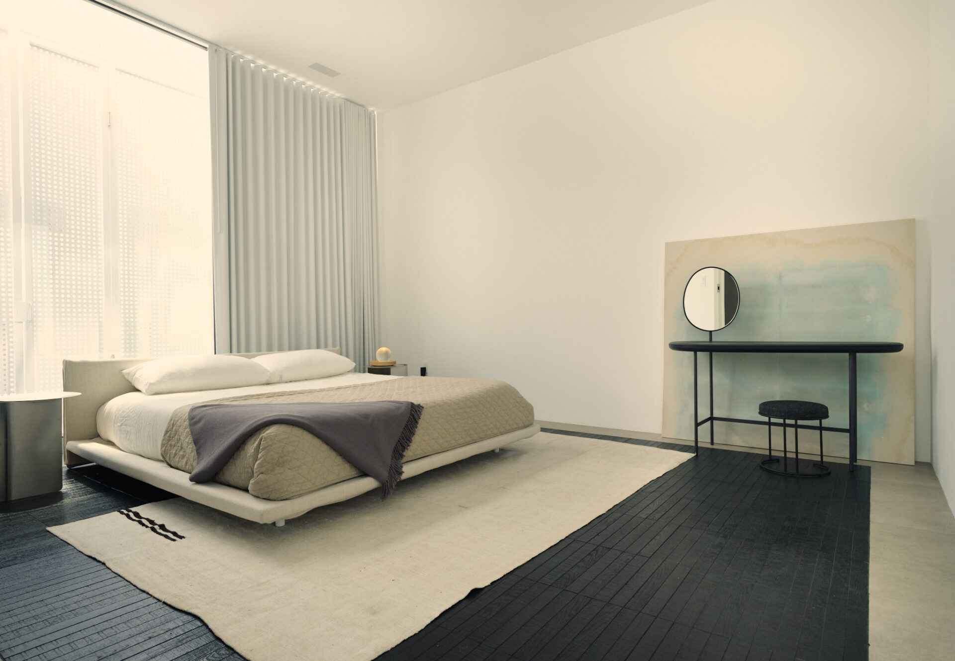 Bedroom with tall ceilings, soft neutral palette, and a corner vanity framed by sheer curtains and abstract pastel artwork.