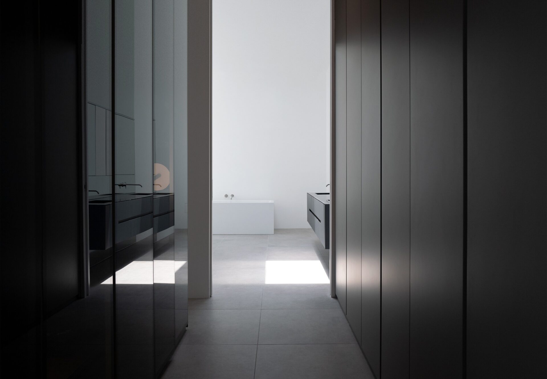 Boutique-style walk-in closet with glossy cabinetry and integrated lighting, opening to en suite with freestanding tub.