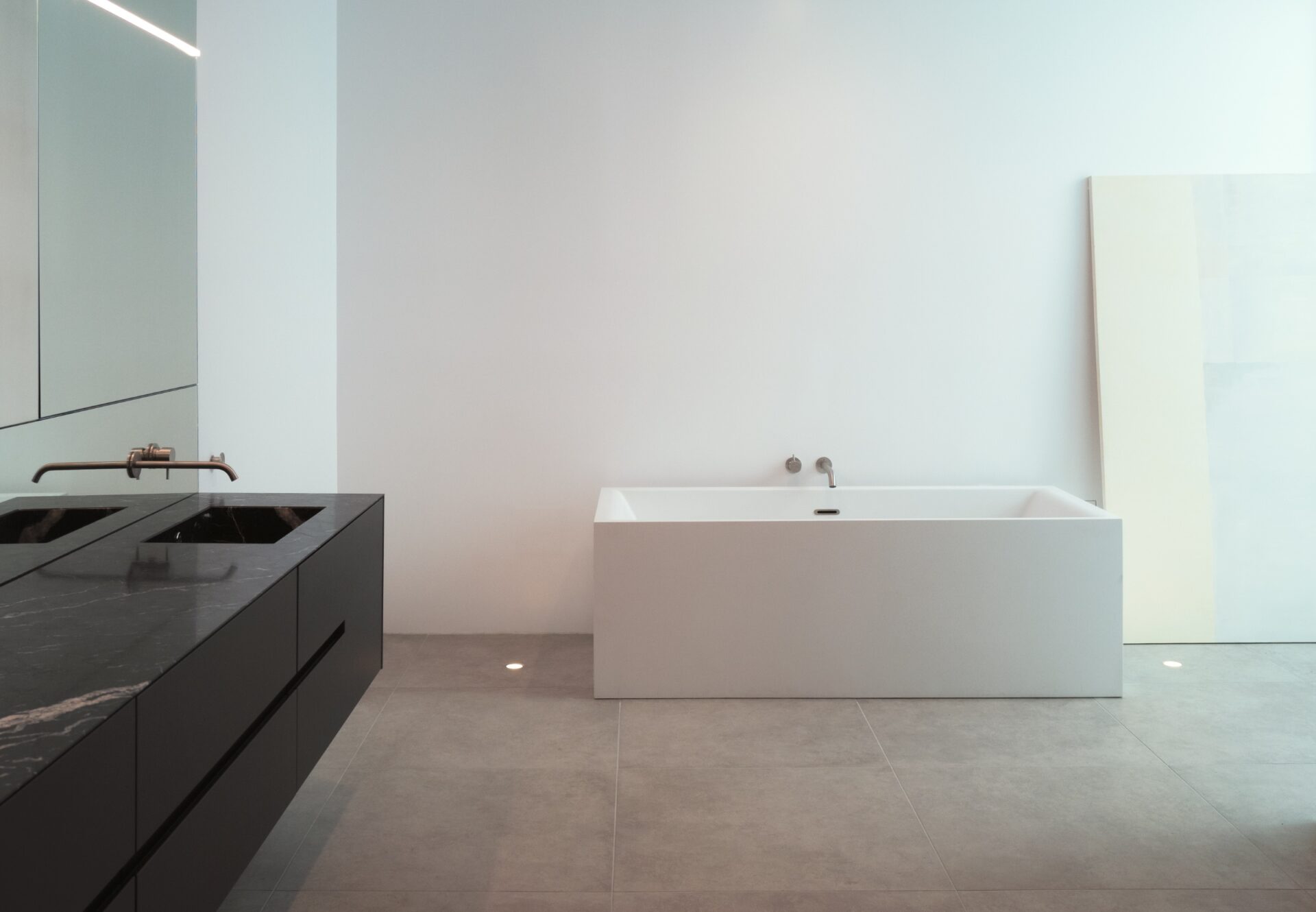 Luxury two-bedroom bathroom with a freestanding soaking tub, double vanity with black marble counters, and large tile flooring.
