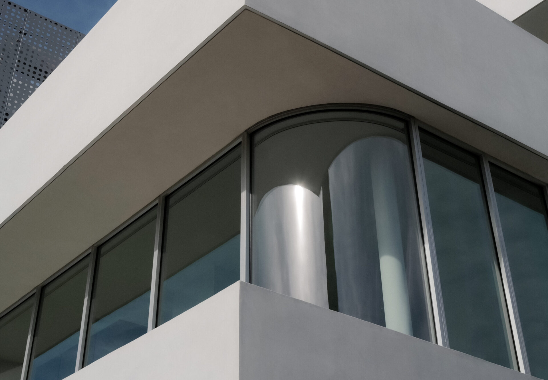 Close-up of curved glass windows reflecting natural light.