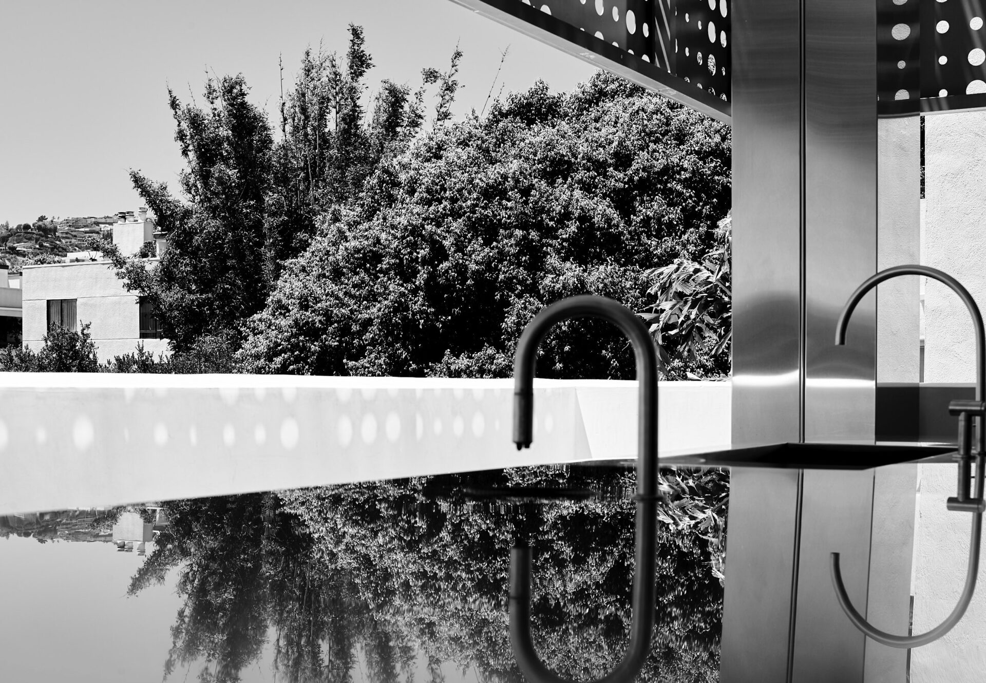 Cafe bar on the Asteras Kings terrace in West Hollywood, featuring sleek black fixtures and reflections of surrounding greenery