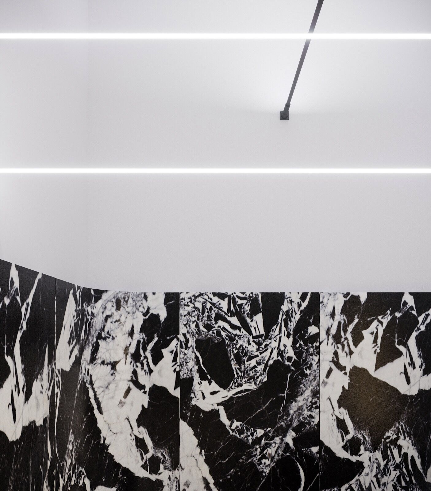 Striking black and white marble wall in the concierge lobby, accented by clean white walls and linear ceiling lighting.